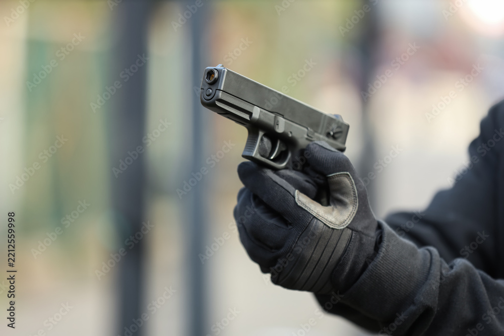 Obraz premium Gun violence and crime prevention person in tactical gloves holding a semi-automatic pistol for security self-defense or law enforcement training
