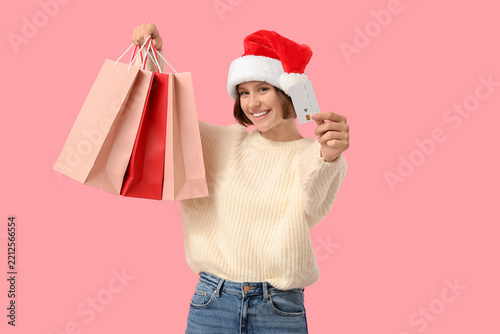 Beautiful young happy woman in Santa hat with shopping bags and credit card o...