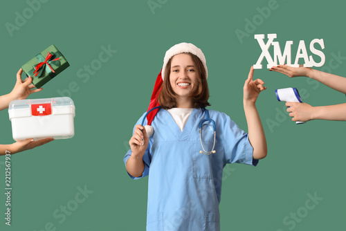 Female doctor in Santa hat and many hands holding gift, thermometer and first...