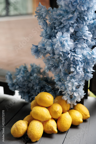 Obraz na plátně A vibrant pile of fresh yellow lemons resting below delicate blue artificial flo
