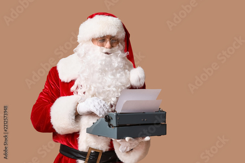 Santa Claus with vintage typewriter on brown background