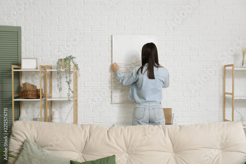 Home improvement and interior design, woman hanging blank canvas on white bri...
