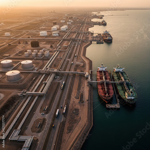 Aerial view of coastal oil terminal storage facility with docked crude tankers at sunset stock image.