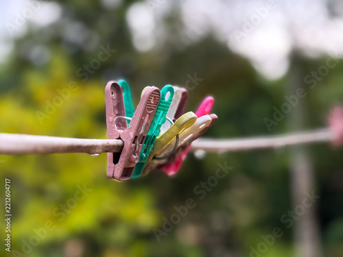 Many colorful plastic clothespin hanging on the wire with raindrop