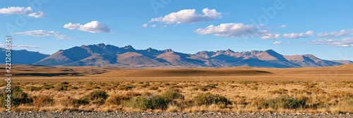 Panel kuchenny z motywem Wide landscape of golden steppe with distant mountain range under blue sky with scattered clouds