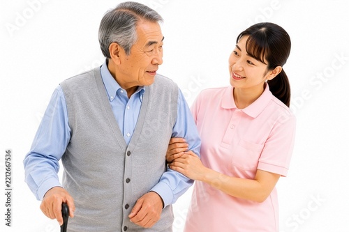 杖を使って歩く高齢男性の腕を優しく支える女性介護スタッフの人物素材、歩行介助や自立支援を行う高齢者介護のイメージ