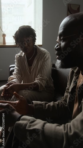 Vertical shot of African American man speaking and gesturing during counseling session with African American woman. Ideal for mental health, therapy, and psychological wellness advertising