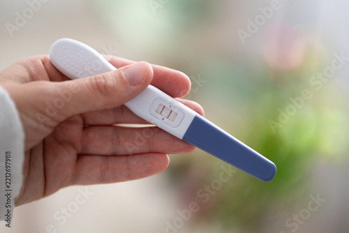 Fotografie Close-up of hand holding home pregnancy test with two visible lines as positive result