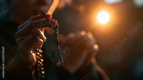 Person Holding Rosary with Crucifix While Praying in Sunlight