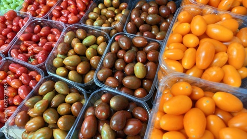 Obraz na plátně Fresh red, green, brown and orange cherry tomatoes arranged in clear market cont