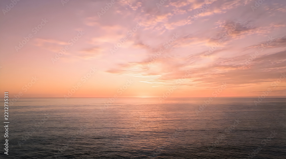 Fototapeta premium A serene ocean view during a beautiful pastel sunset with soft clouds above the calm water horizon