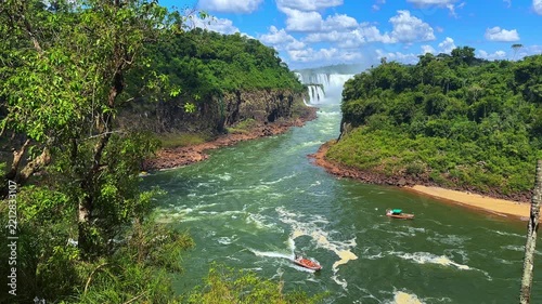 Scenic view of Iguazu Falls in Argentina with lush green jungle and tourist boats on the river