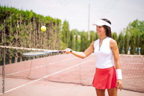 Woman playing tennis on court hitting ball