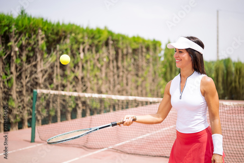 Woman playing tennis hitting a yellow ball