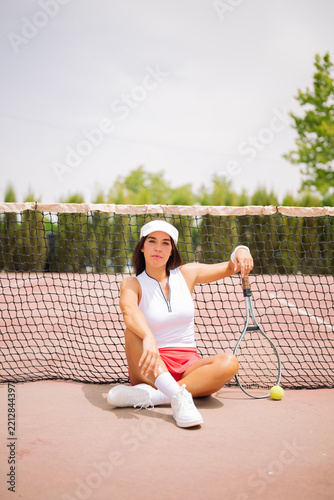 Woman tennis player sitting on court by net