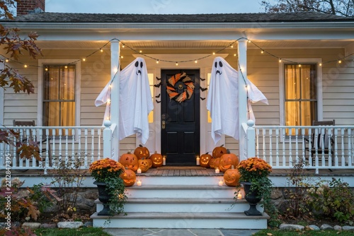 Halloween decorated front porch with hanging white ghost figures and pumpkins