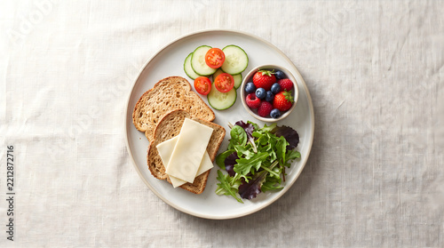 A delicious cheese healty meal served on a plate with whole grain bread, fresh green salad, and sweet berries.