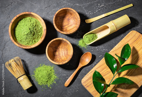Professional matcha green tea preparation set with bamboo whisk on black stone surface