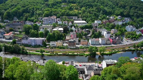 Aerial panoramic view of a scenic German town nestled along a river and lush green forest hills

