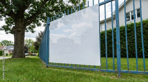 Blank white sign hanging on a blue metal fence