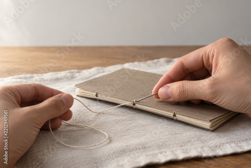 Hands stitching handmade notebook using traditional Japanese binding method