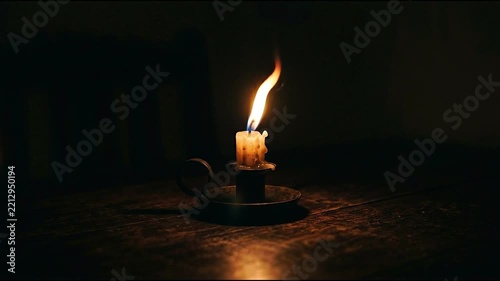 A burning candle with a bright flame against a dark background