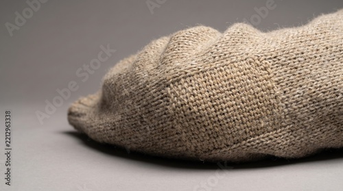Close-up of a beige wool sweater with elbow repair on a neutral