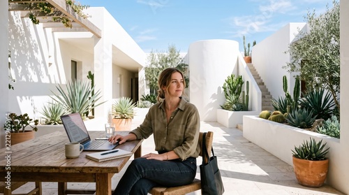 Woman using laptop in bright desert courtyard