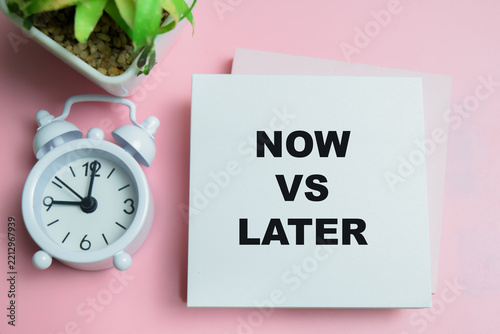 Concept of now vs later write on sticky notes isolated on table.