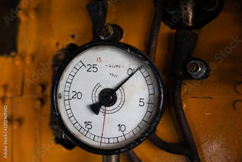 Close-up of a vintage industrial pressure gauge meter on a yellow metallic background, retro machinery and equipment.