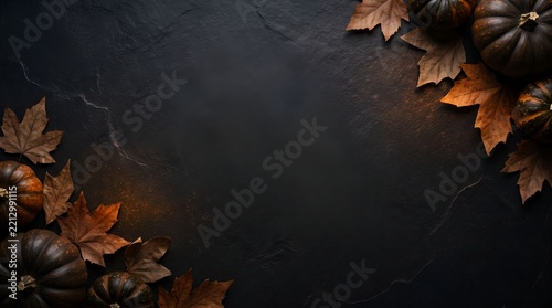 Dark textured background with scattered autumn maple leaves and small pumpkins