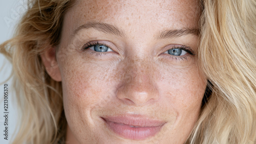 Close up portrait of a natural woman with blonde hair, blue eyes, and freckles, presenting authenticity, beauty, and confidence for skincare and health concepts