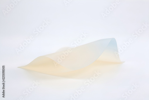 Translucent frosted sheet folded into a gentle wave in a minimalist studio