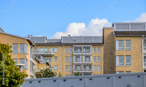 Modern brick apartment buildings beneath clear Scandinavian summer sky.