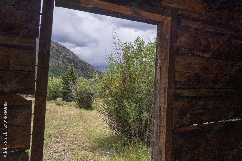Fototapeta premium View Through Doorway of Abandoned Log Cabin to Mountain Valley