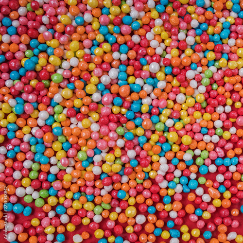Colorful sugar sprinkles texture on red, full frame