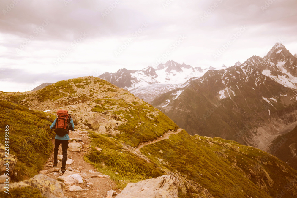 Obraz premium Hiker exploring scenic mountain trail under cloudy sky