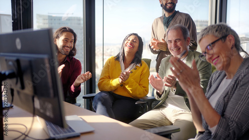 Diverse group of professionals applauding and celebrating together during an office meeting. Positive corporate scene conveying achievement, recognition, teamwork and shared success.