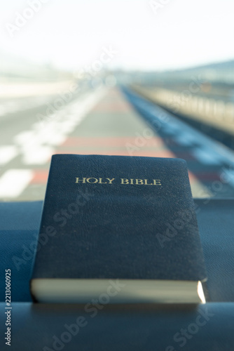 Holy Bible photographed on Japan's Tomei Expressway, with a bright overexposed and softly blurred background that emphasizes the Bible as the central subject.