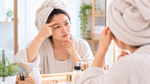 お風呂上がりに鏡で眉間のシワを確認する中年女性