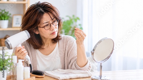 ドライヤー後に抜けた髪の毛を確認する中年女性