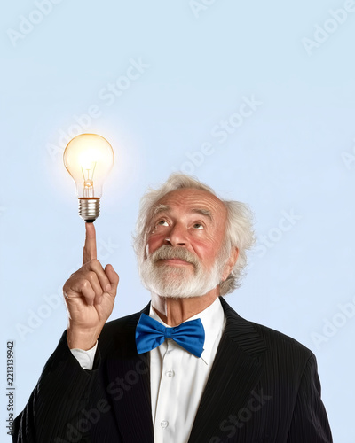 Elderly Man with White Beard and Blue Bow Tie Balancing Glowing Lightbulb on Fingertip, Symbolizing Inspiration and Brilliant Idea, Pinstripe Suit, Light Blue Background, Vertical 8x10, Copy Space.