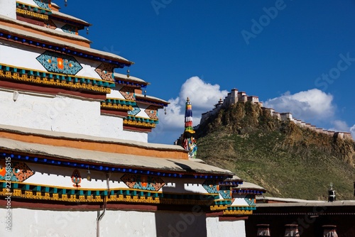 Kumbum Stupa of Pelkor Chöde Monastery in Gyantse, Tibet, with the ancient Gyantse Dzong fortress on a rocky hilltop, showcasing Tibetan Buddhist architecture in the Himalayas.