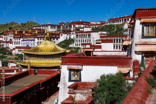 Golden-roofed temple and whitewashed monastery buildings with red trim at Ganden Monastery in Dagze, Tibet, a historic Gelug Buddhist landmark in the Tibetan Himalayas.