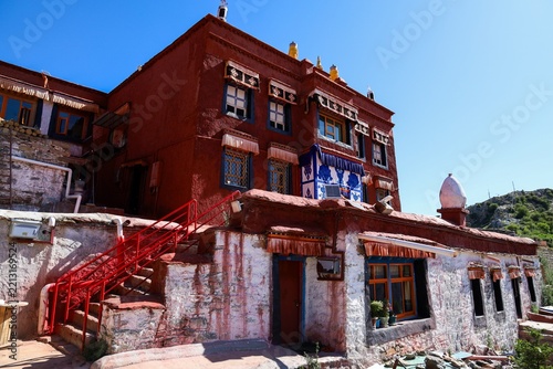 Red-walled prayer hall with a red staircase at the top of Ganden Monastery in Dagze, Tibet, a historic Gelug Buddhist monastery and iconic Himalayan landmark.