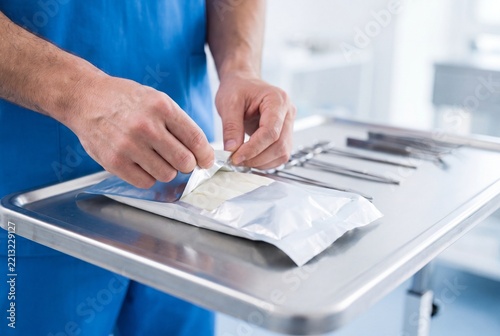 Doctor Opening Sterile Package with Medical Equipment on Stainless Steel Tray