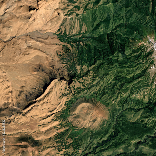 Aerial view featuring mountains covered in lush green forests blending into flatter