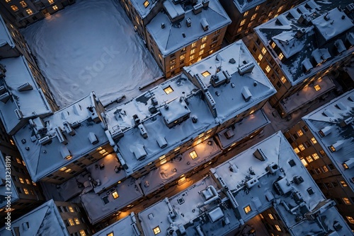 Snowy cityscape at dusk with illuminated buildings.