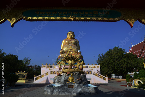 A large brilliantly gold-colored statue of Phra Maha Kaccayana Thera, holding a holy water vessel representing the 76 provinces standing 20 meters at Wat Lang San Prasit.