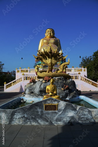 A large brilliantly gold-colored statue of Phra Maha Kaccayana Thera, holding a holy water vessel representing the 76 provinces standing 20 meters at Wat Lang San Prasit.